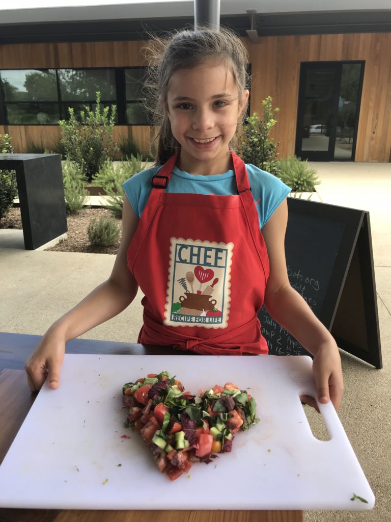 Young girl wearing a CHEF (Culinary Health Education for Families) apron