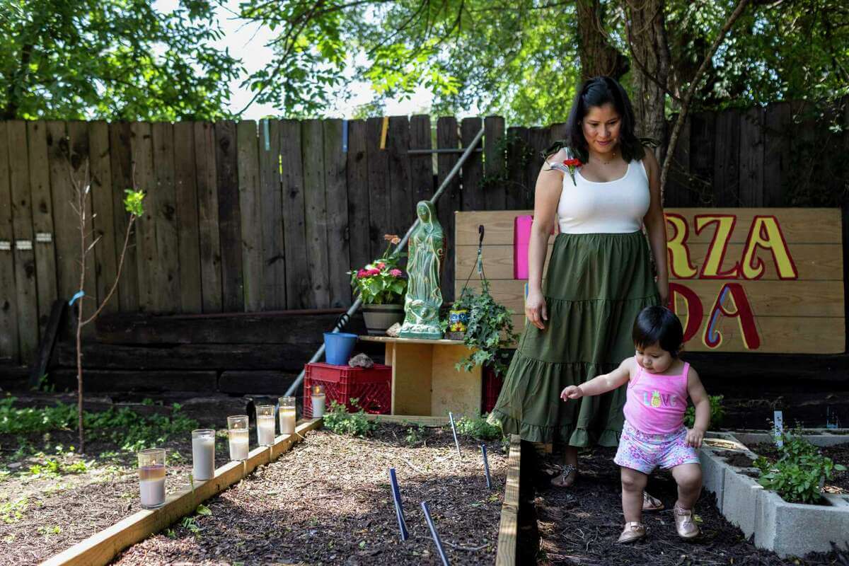 Woman and her young daughter walking in a community garden